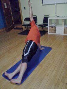 Older man holding yoga pose on yoga mat
