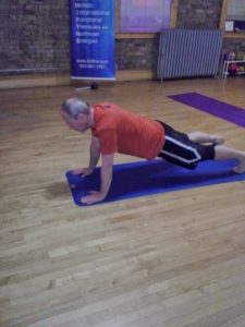 Older man holding yoga pose on yoga mat
