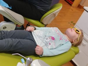 Young girl laying back in chair at dentist's office