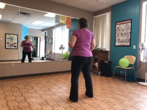 Tammy holding a pose in front of wall mirror at Minneapolis fitness studio