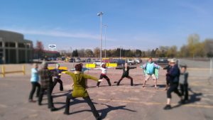 Several adults doing yoga in outdoor parking lot