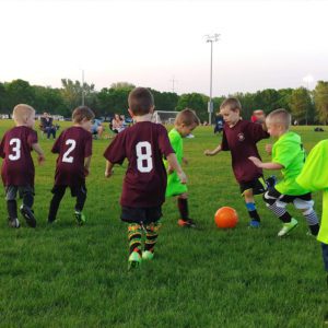 young kids wearing jersey playing soccer on soccer field