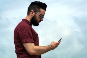 man looking down at phone demonstrating tech neck posture